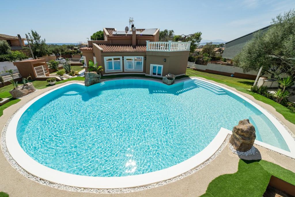 a large swimming pool in front of a house at Villa Leon with Private Pool in Quartu SantʼElena