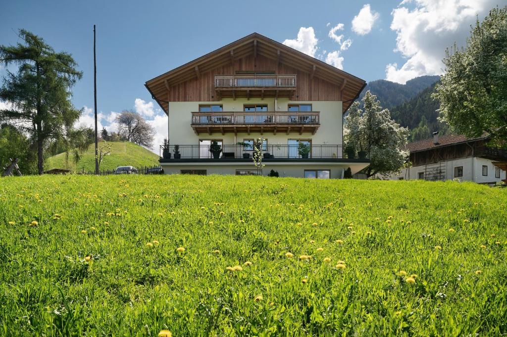 a house on top of a hill with a green field at Baumannhof Villnöß in Funes