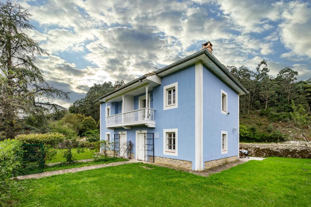 a blue house with a balcony on a yard at La Braña in Bustio