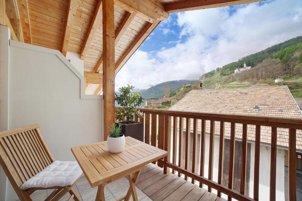 a wooden balcony with a wooden table and chairs at Ferienwohnungen Zwick Valarga in Malles Venosta