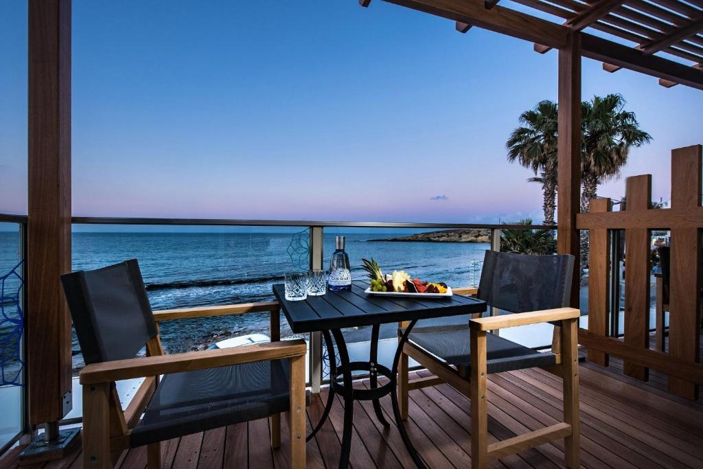 a dining table on a deck with a view of the ocean at Enorme Infinity Beach ex Infinity Blue in Hersonissos