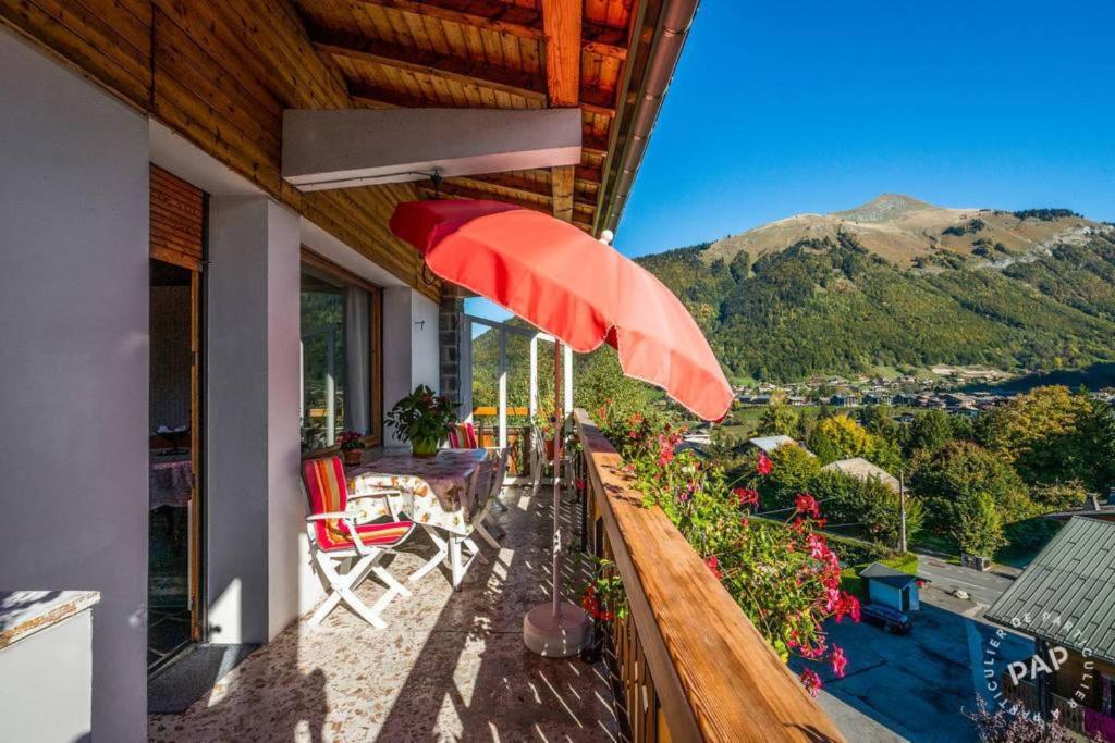 a balcony with a red umbrella and a table and chairs at Apt Morzine 1000 in Morzine