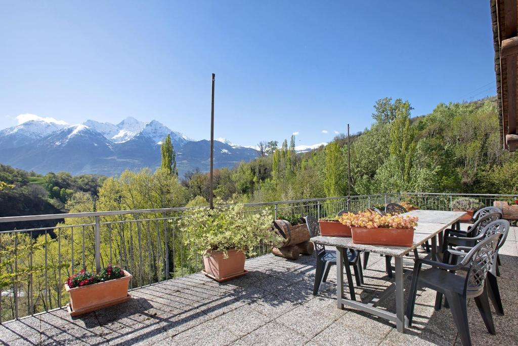 a table and chairs on a balcony with mountains at Eun Tchì Vo - Gignod in Gignod