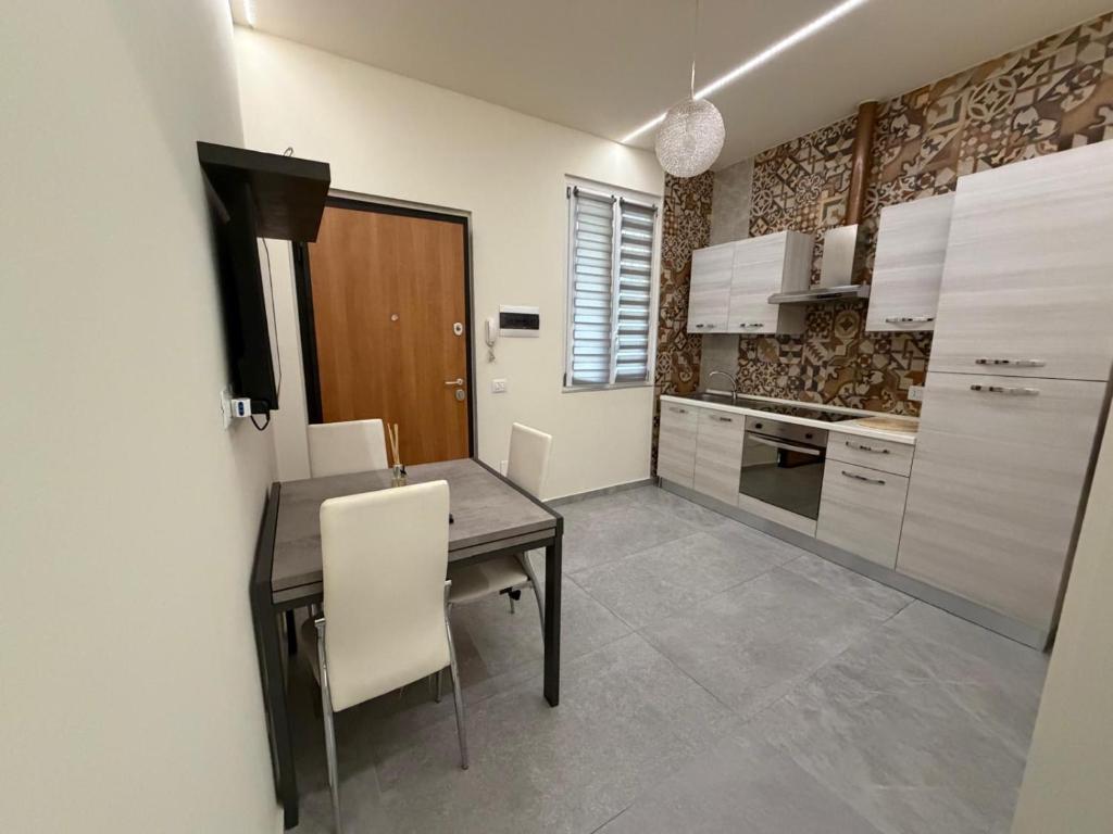 a kitchen with a wooden table and white chairs at Valepiace 1 in Piacenza