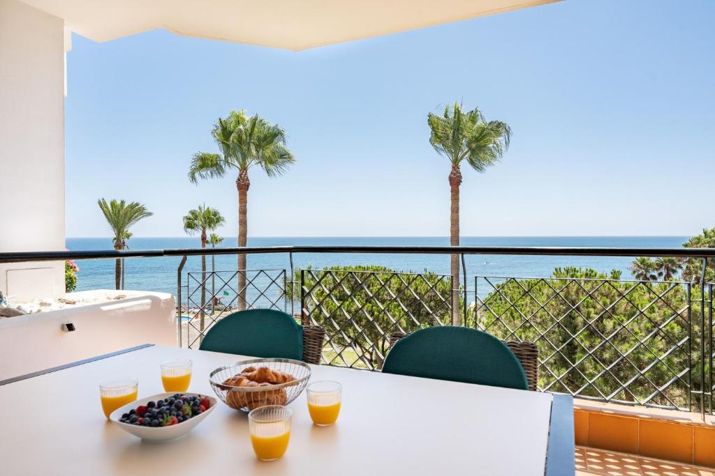 a table with a bowl of fruit on a balcony with palm trees at Mi Capricho Calahonda in Mijas