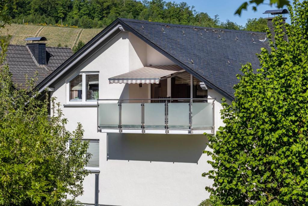 a white house with a balcony and trees at Ferienwohnung Urban in Bestwig