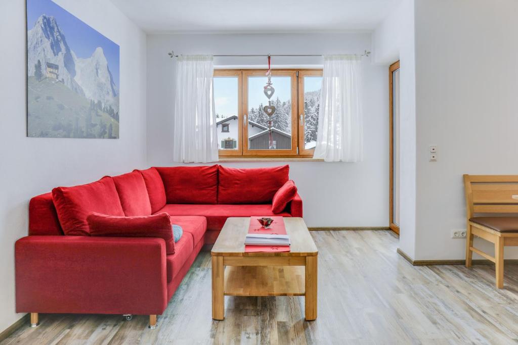 a red couch in a living room with a table at Ferienwohnung Schachen in Garmisch-Partenkirchen