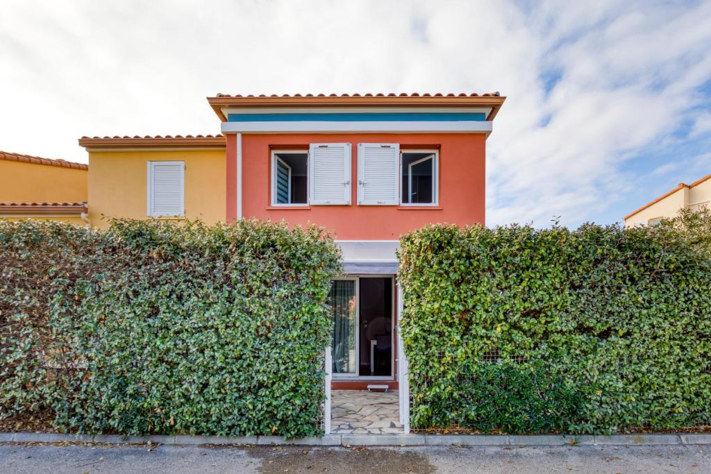 a house with a hedge in front of it at Le Mas de la Mer in Frontignan