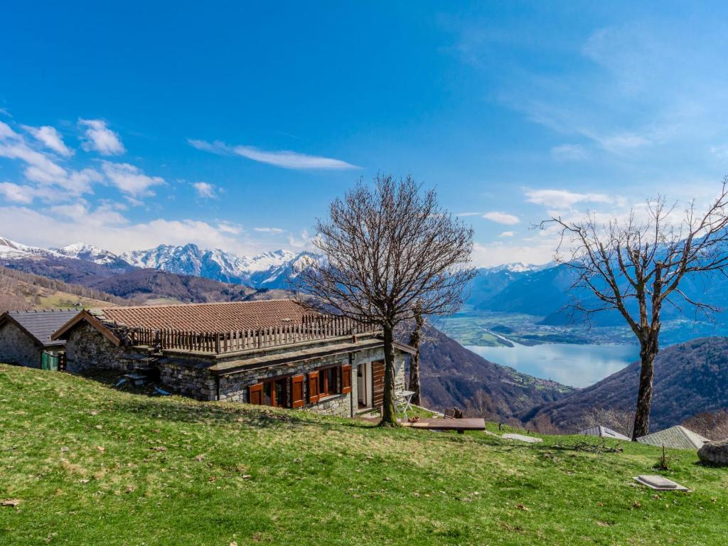 a house on a hill with mountains in the background at Chalet Baita Santina by Interhome in Peglio
