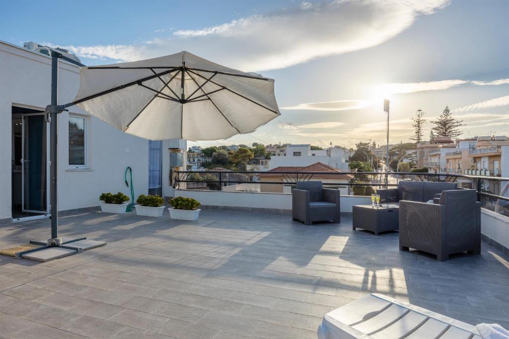 a patio with an umbrella and chairs on a roof at La Terrazza Di Porticello in Porticello