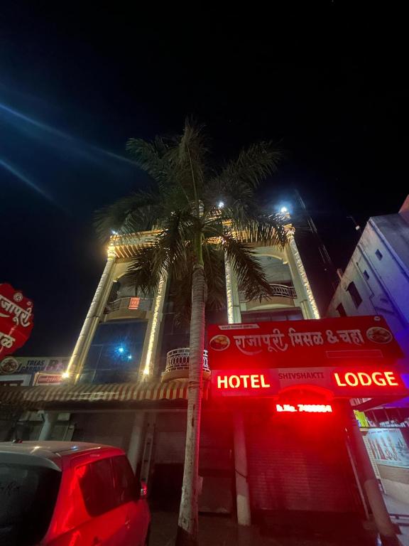 a hotel with a palm tree in front of a building at Hotel Shiv-Shakti in Solapur