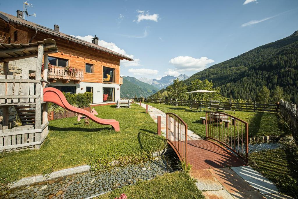a house with a slide in the grass next to a building at Bruneggerhof Weissenbach in Rio Bianco