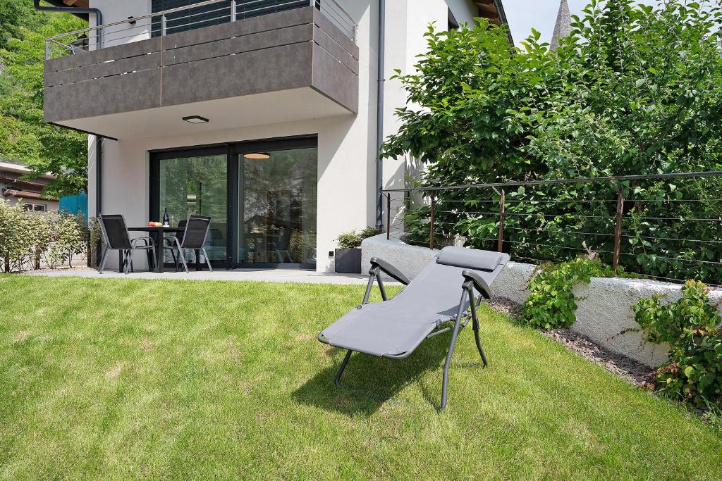 a chair sitting in the grass in front of a house at Haus Weinblick Apt 3 in Magrè allʼ Adige