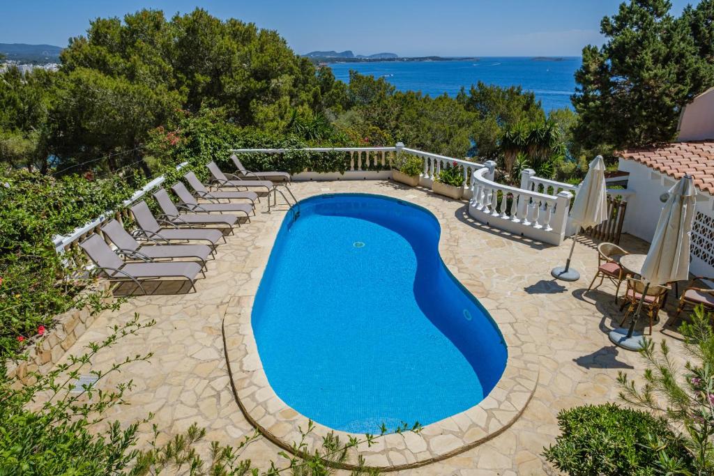 a swimming pool with lounge chairs around it and the ocean at Shangri-la in Santa Eularia des Riu
