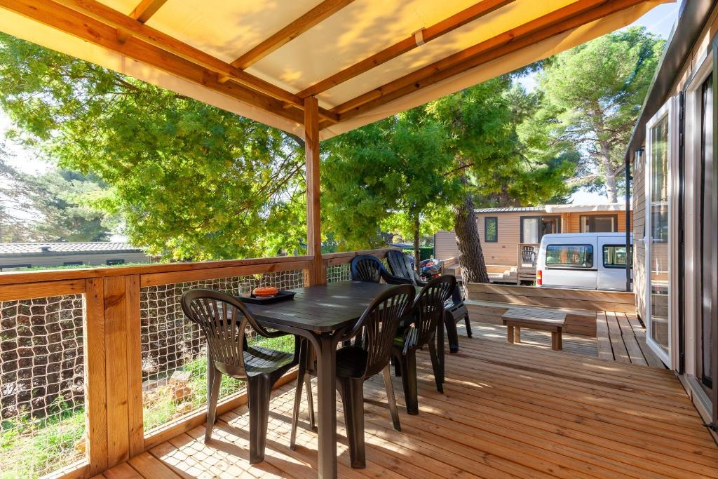 a wooden deck with a black table and chairs at Camping Lou Soulei 218 in Carry-le-Rouet
