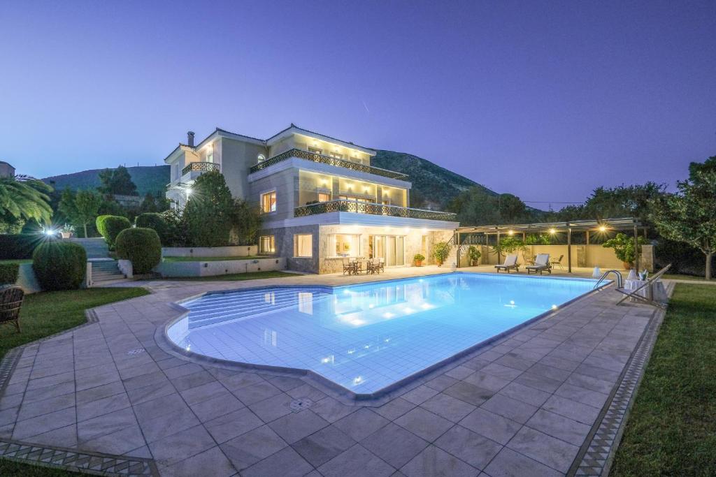 a large house with a swimming pool in front of it at Supreme and Classy Pool Residence in Paianía