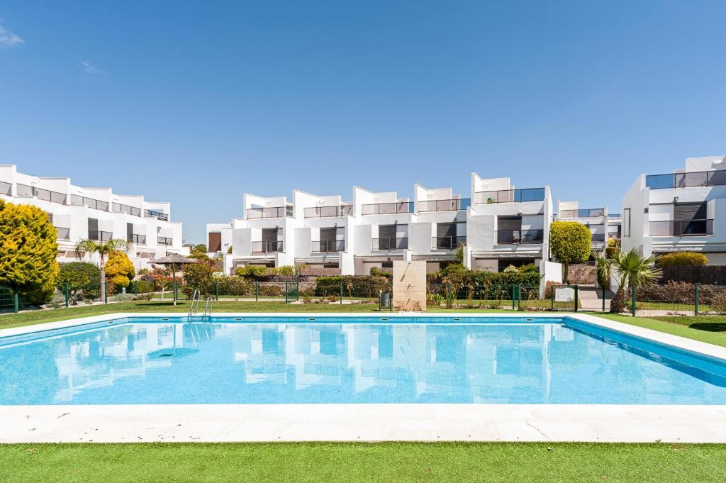 a swimming pool in front of a large apartment building at Casa Alena in Conil de la Frontera