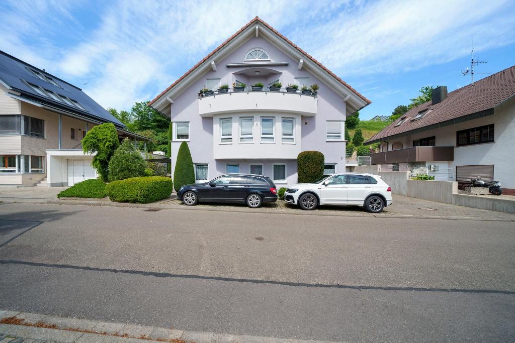 two cars parked in front of a white house at Haus Am Weinberg 2 in Endingen