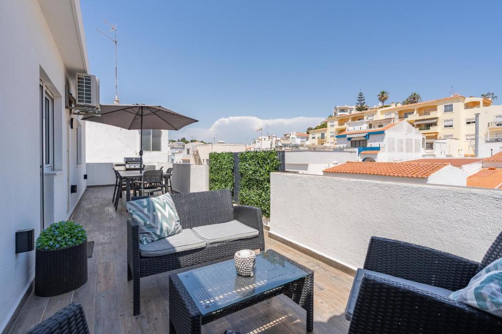 a balcony with chairs and a table and an umbrella at Casa Terrace Carvoeiro in Carvoeiro