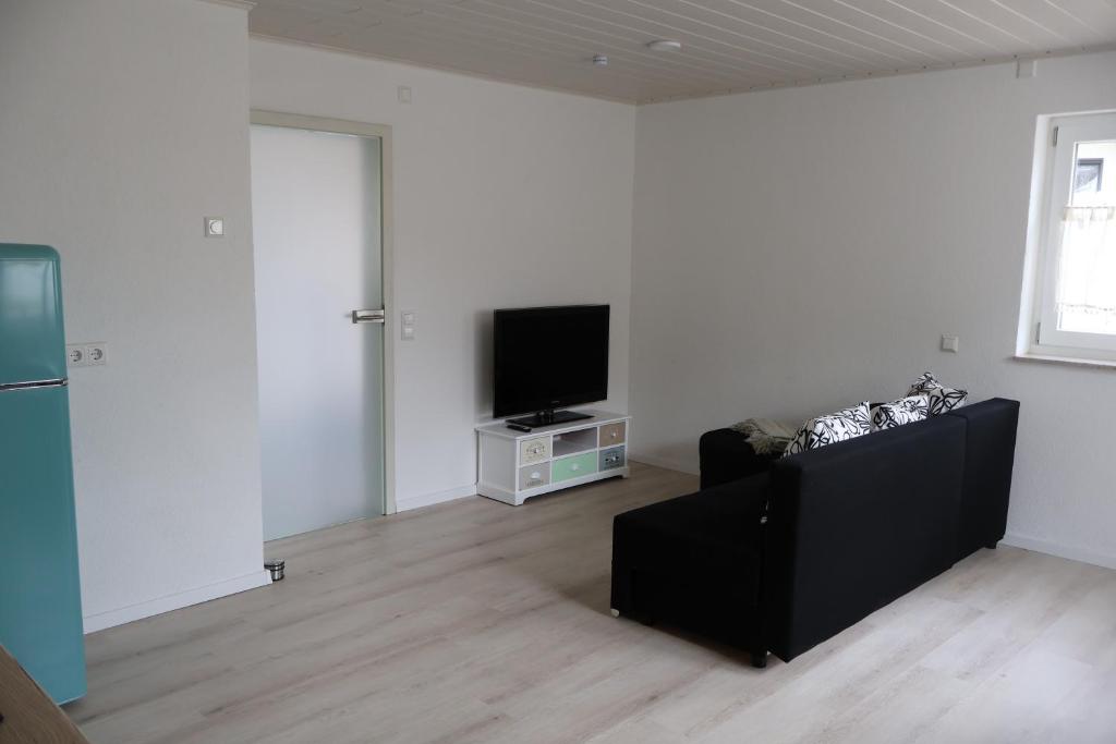 a living room with a black couch and a tv at Ferienwohnung Spielmann in Sauldorf