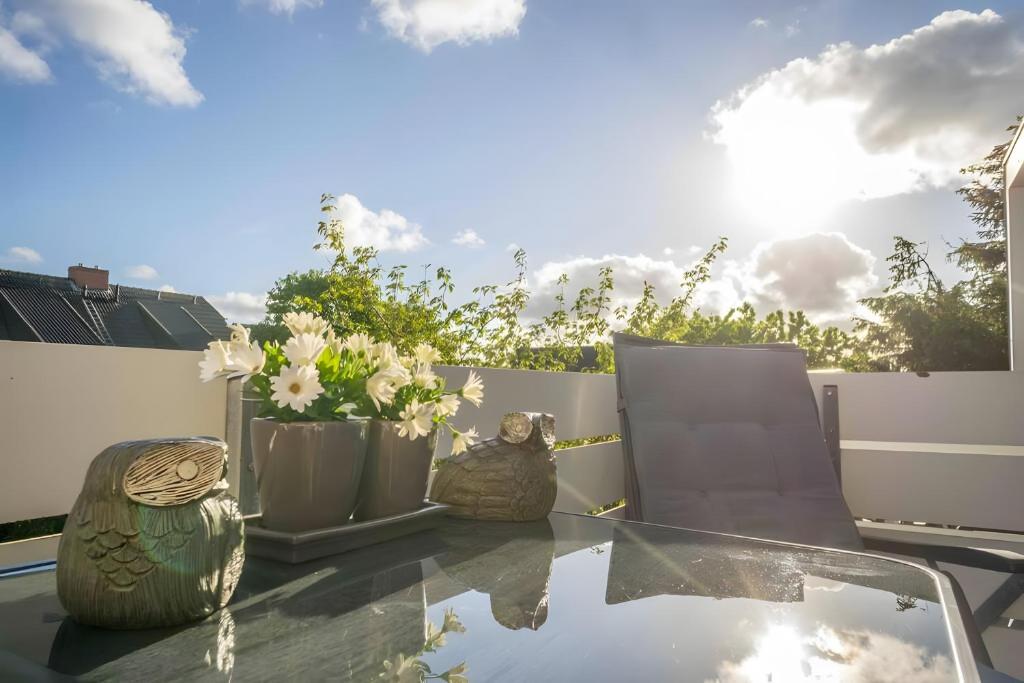a glass table with vases and flowers on a balcony at Tolle Wohnung mit Sonnenbalkon in Wenningstedt
