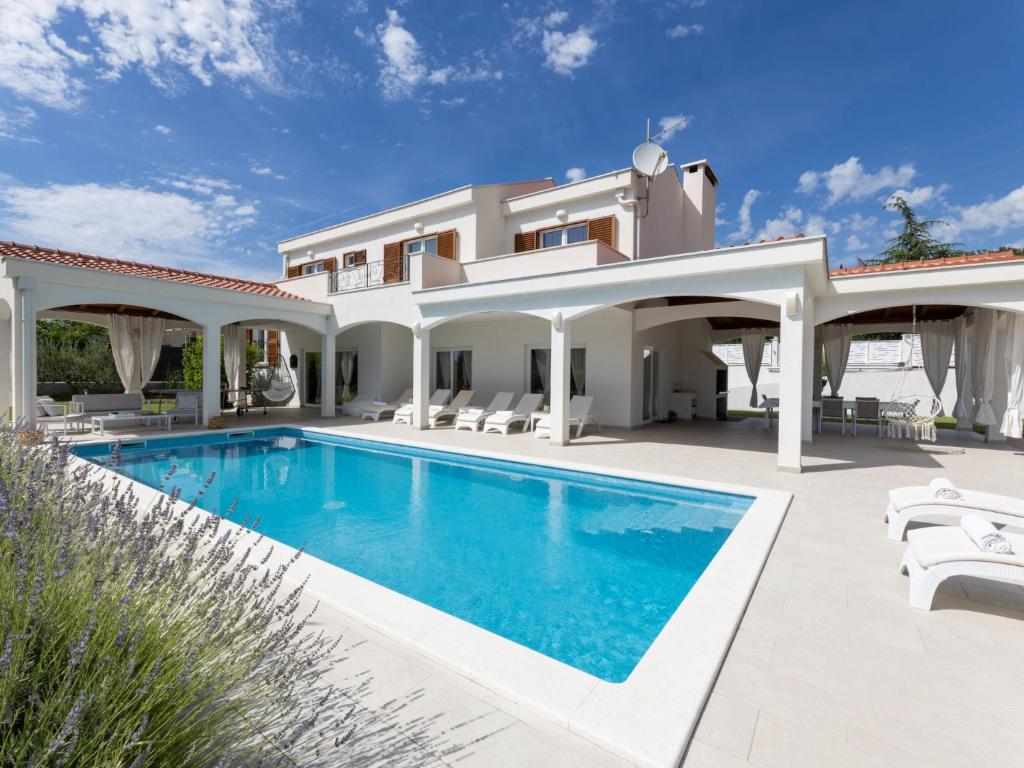 a villa with a swimming pool in front of a house at Villa Olivia by Interhome in Šestanovac