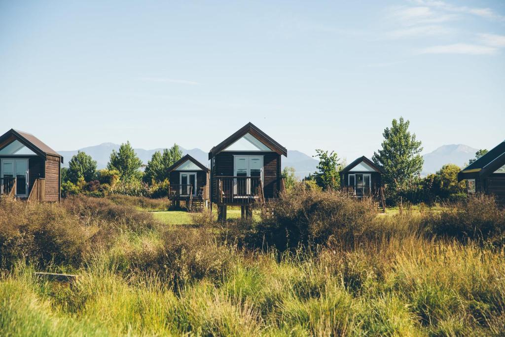 a row of cottages in a field of grass at Appleby House & Rabbit Island Huts in Mapua