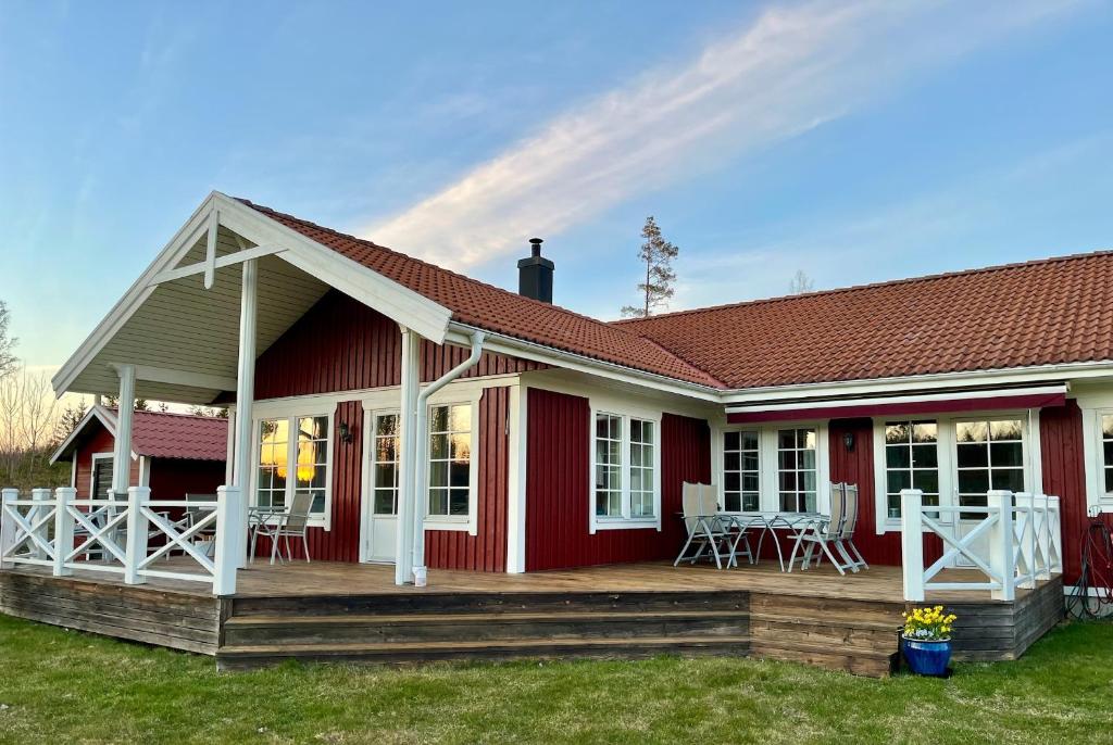 a red and white house with a deck at Aspudden en pärla i Sörmland in Vingåker