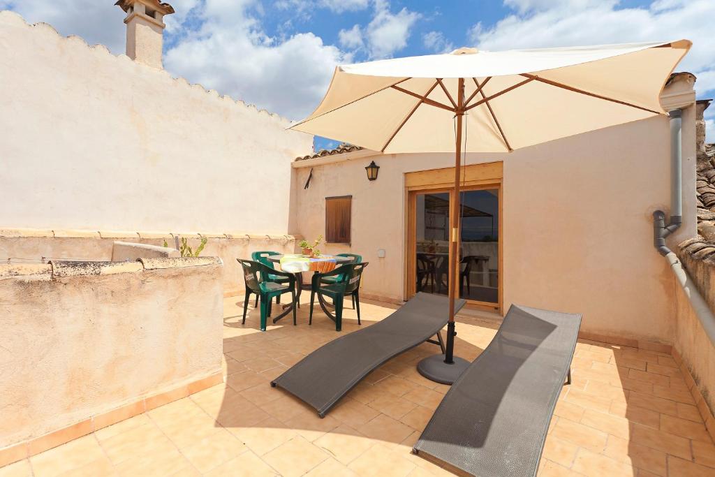 a patio with an umbrella and a table and chairs at Sa Raval in Maria de la Salut