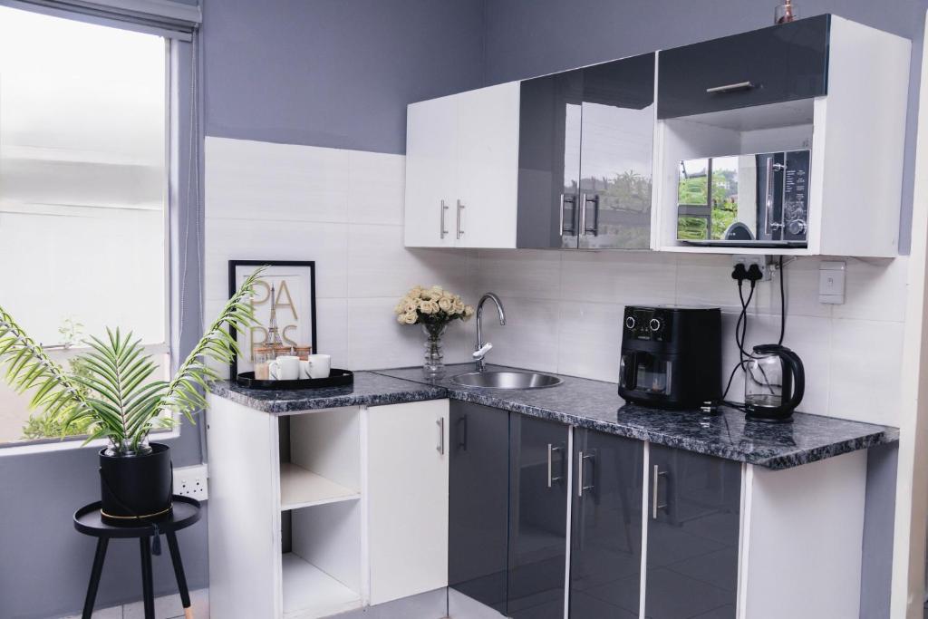 a kitchen with white cabinets and a sink at Bachelor suite in Rustenburg in Rustenburg