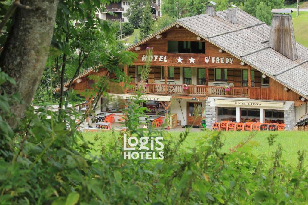 a large wooden house with orange chairs in front of it at Logis Hôtel Restaurant U'Fredy in La Clusaz
