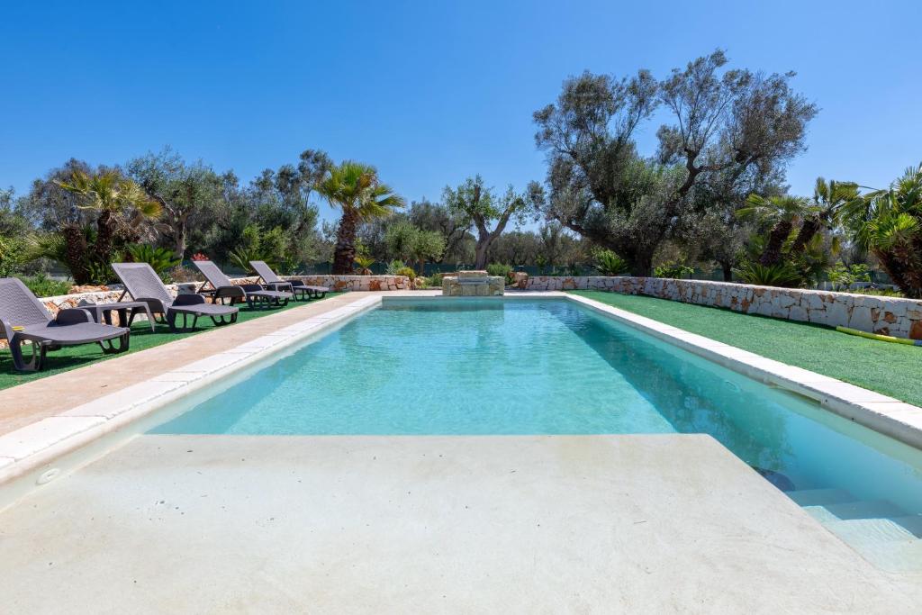 a swimming pool in a yard with chairs and trees at Il Canto della Cicala in San Vito dei Normanni
