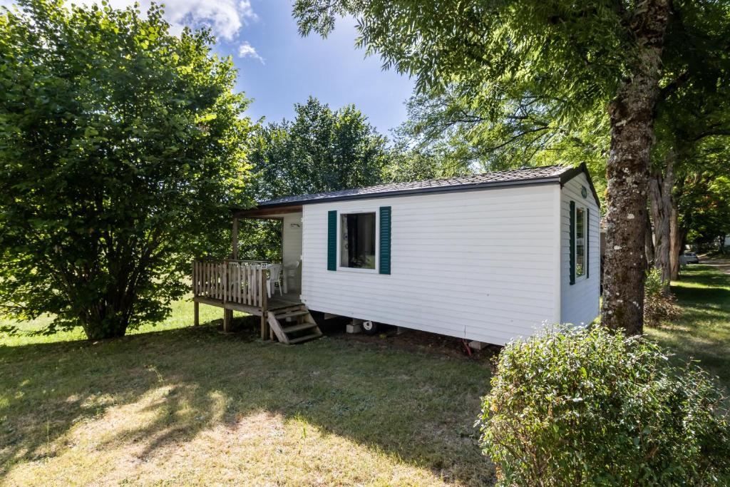 a white tiny house with a bench in a yard at Mobilhome du Soleil in Saint-Pompont
