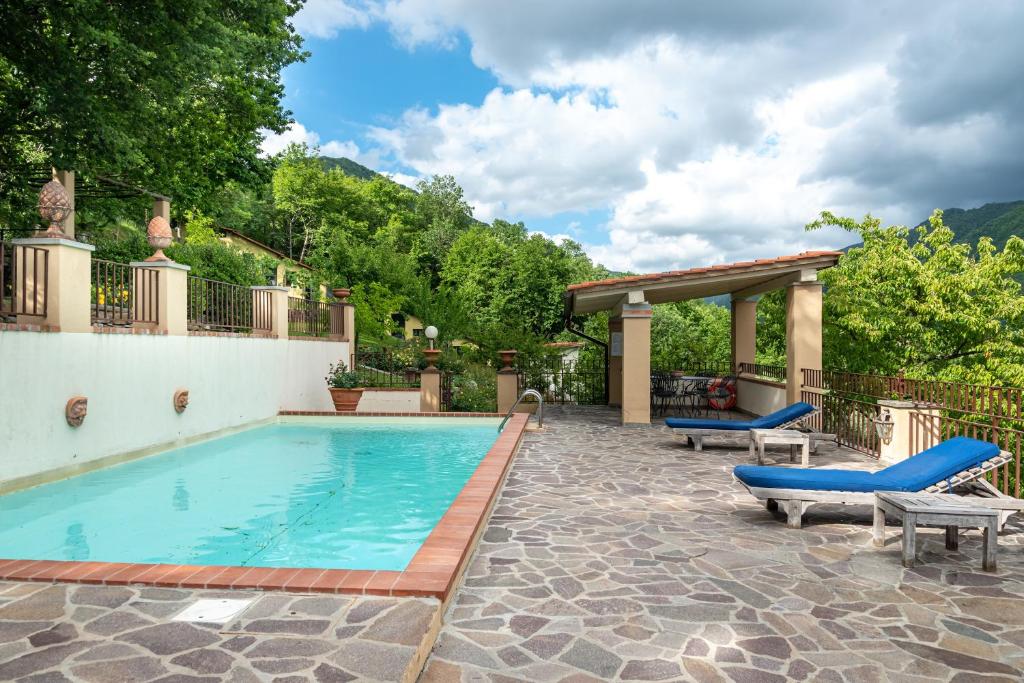 a swimming pool with two lounge chairs and a patio at Villa L'incompiuta in Gattaia