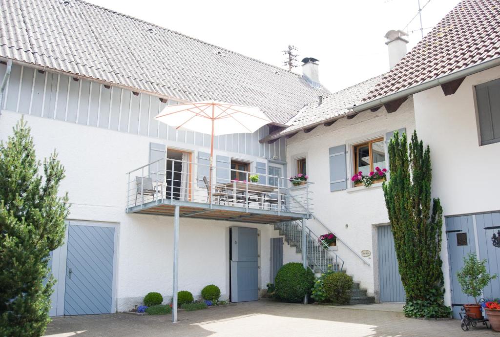 a white house with a balcony and an umbrella at kleines Landhaus Bodensee in Überlingen