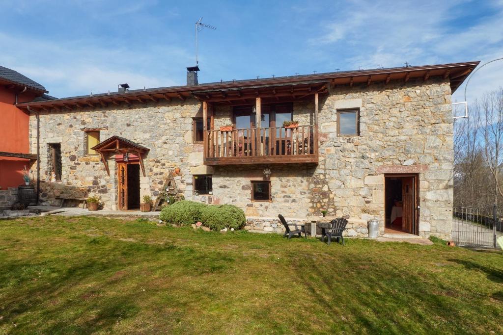 a stone house with a deck on the side of it at El Mirador de Babia in Ríolago
