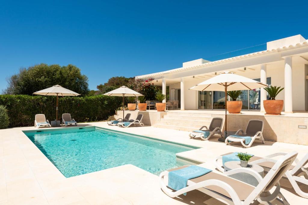 a villa with a swimming pool with chairs and umbrellas at Villa Mariposa in Sant Lluis