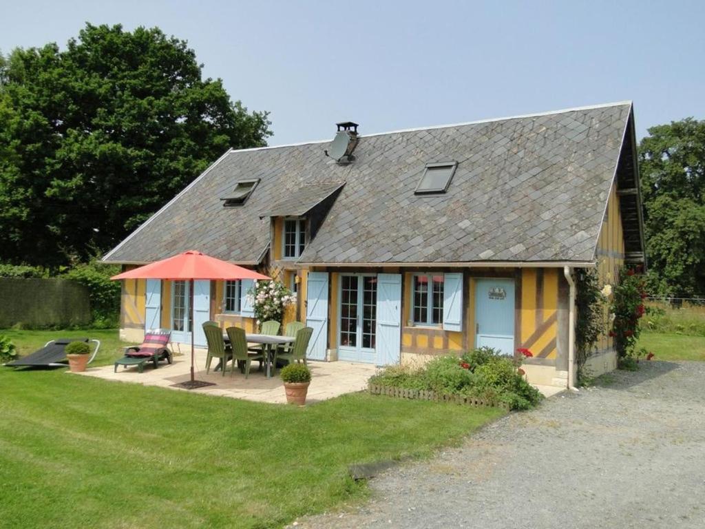 a small house with a patio and a table and umbrella at Le Pressoir in Cresseveuille