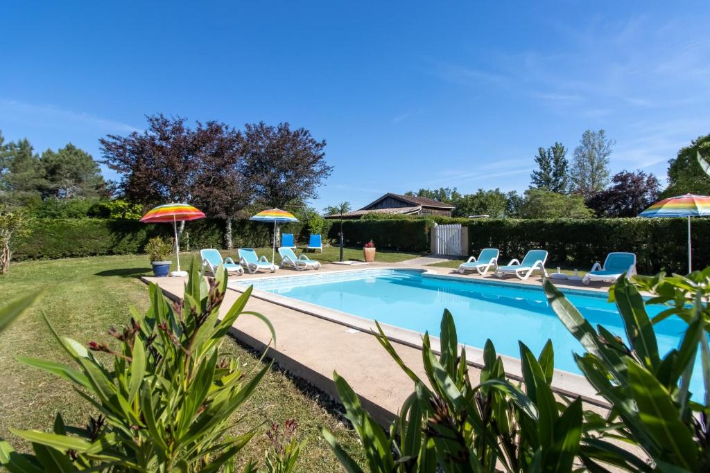 a swimming pool with chairs and umbrellas at Gite à la campagne in Ginestet