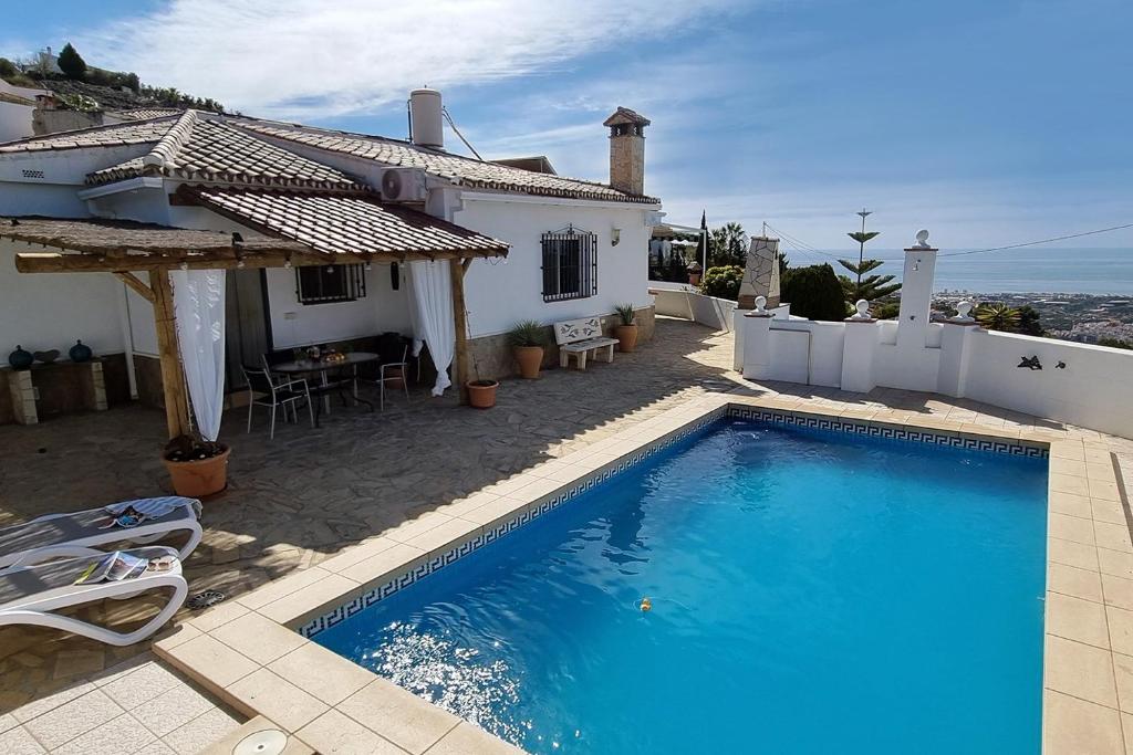 a villa with a swimming pool in front of a house at Casa La Paz in Torrox