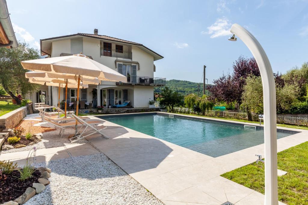 a swimming pool with an umbrella and a house at Villa La Lanterna Bianca a Bagnone in Bagnone