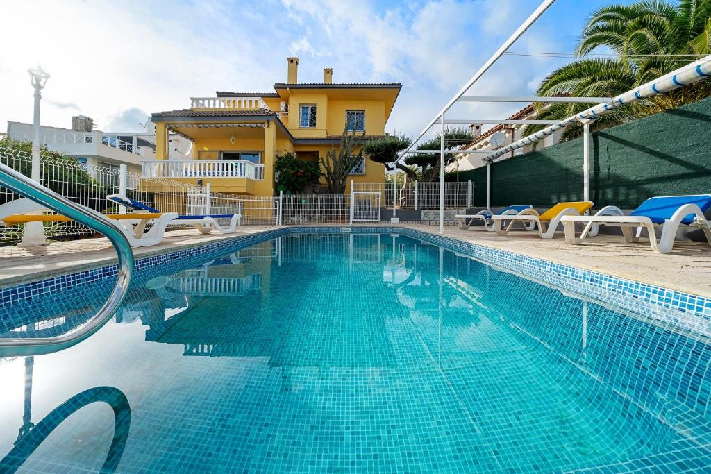 a swimming pool with chairs and a house in the background at Villa Amador in L'Ampolla