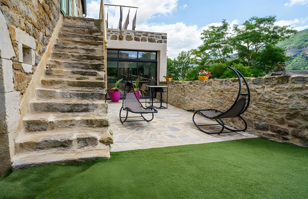 a patio with two chairs and a stone wall at Gite Sublime Spa, Piscine Indoor in Mostuéjouls