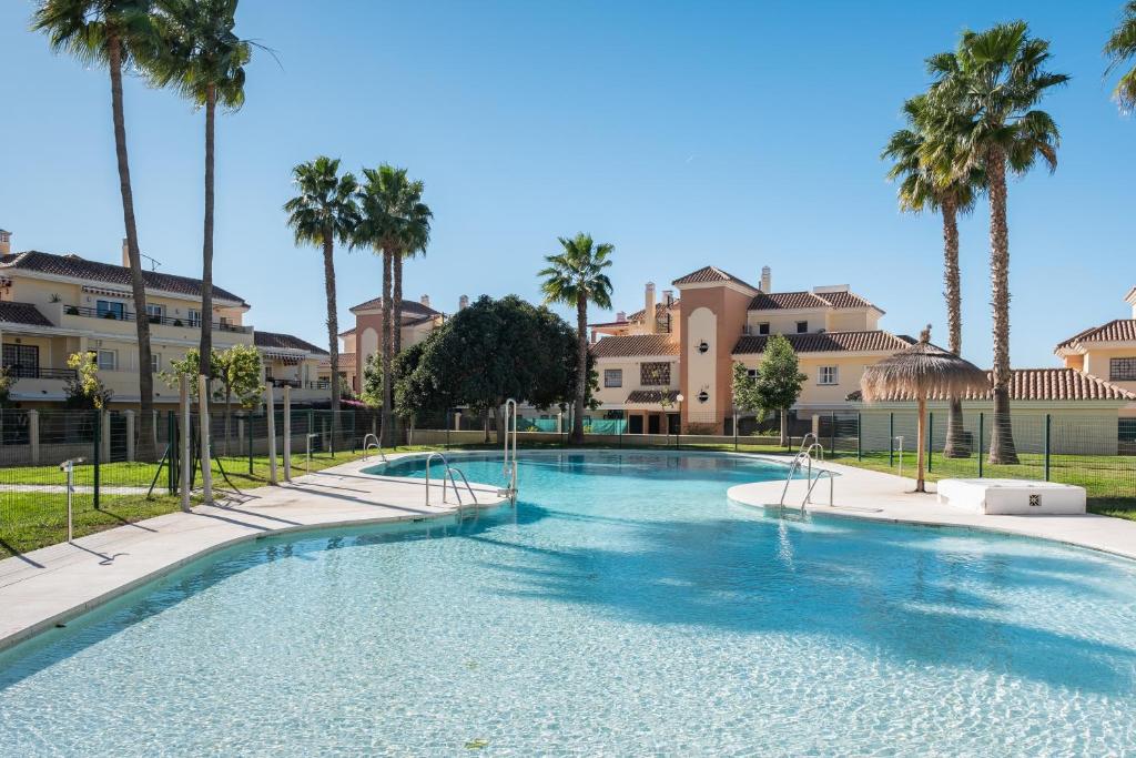 a large swimming pool with palm trees and buildings at Baviera Homes Sunset and Golf in Caleta De Velez
