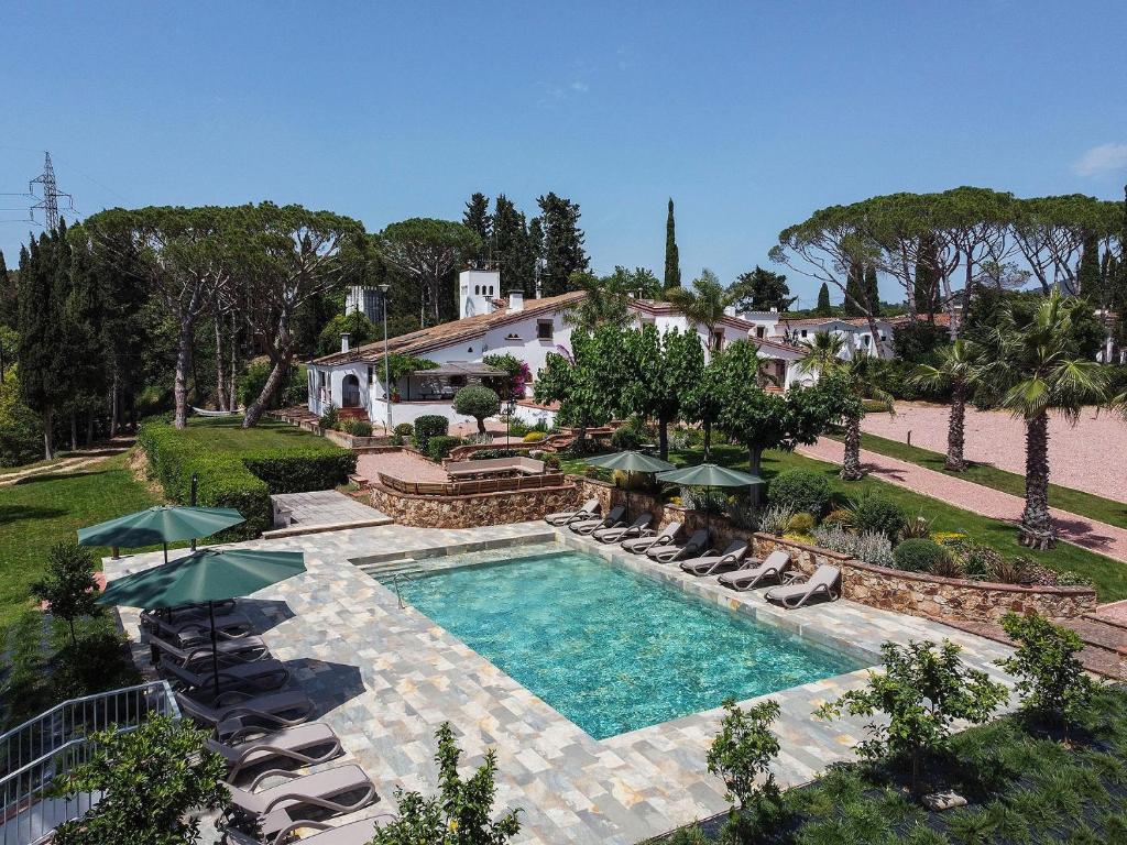 an overhead view of a swimming pool with chairs and umbrellas at Masia Luxmarspa in Tordera