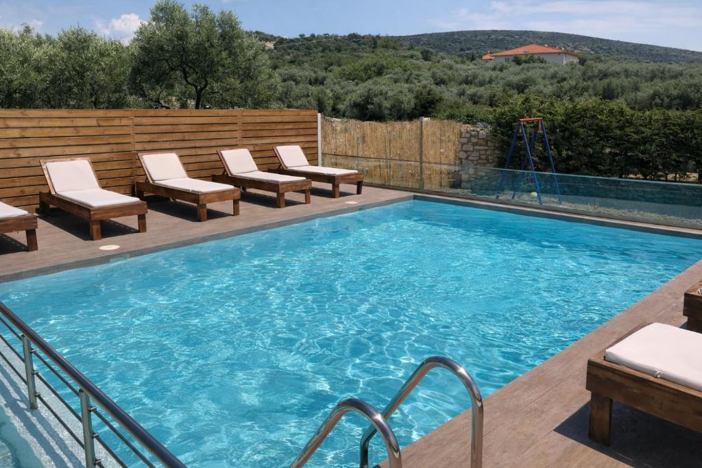 a swimming pool with lounge chairs next to a wooden fence at Studios River - Potos Escape with Pool and Views in Potos