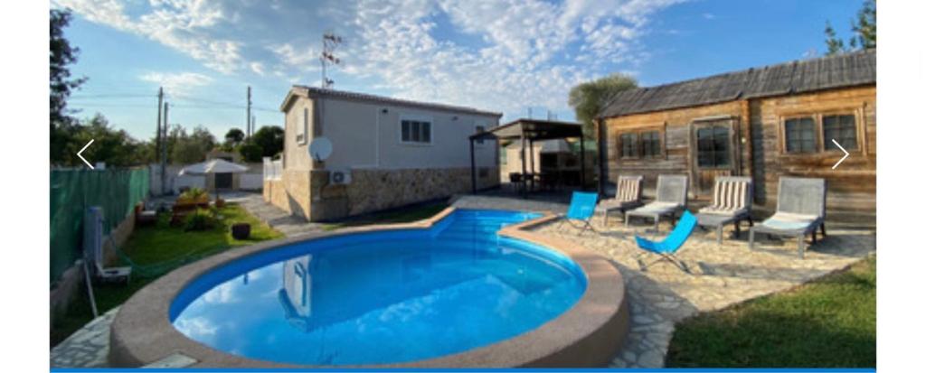 a swimming pool in a yard with chairs and a building at Can dennis in Sils