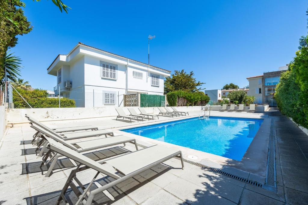 a swimming pool with lounge chairs next to a building at La Plaza in Port de Pollensa