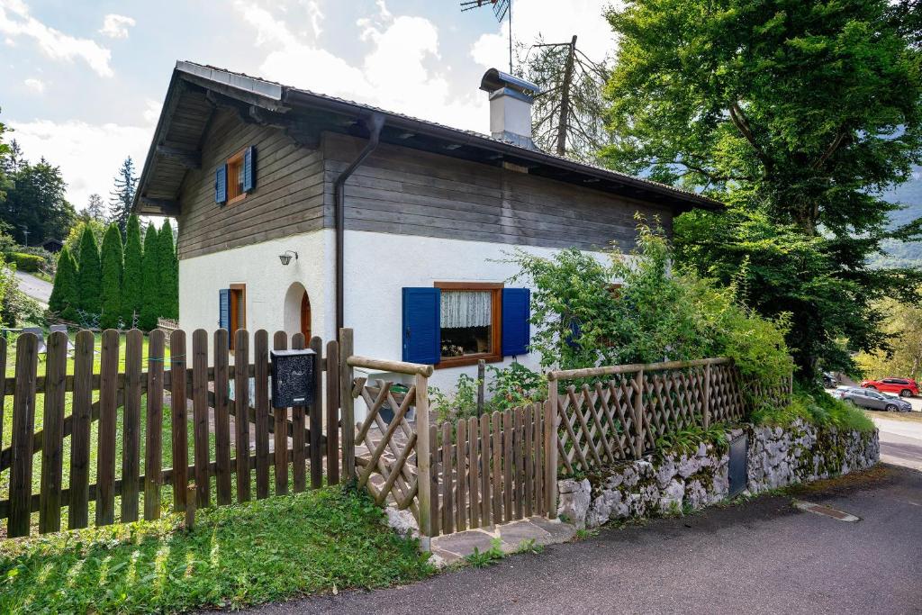 a small house with a wooden fence in front of it at Casa Belfort per 9 persone in Spormaggiore