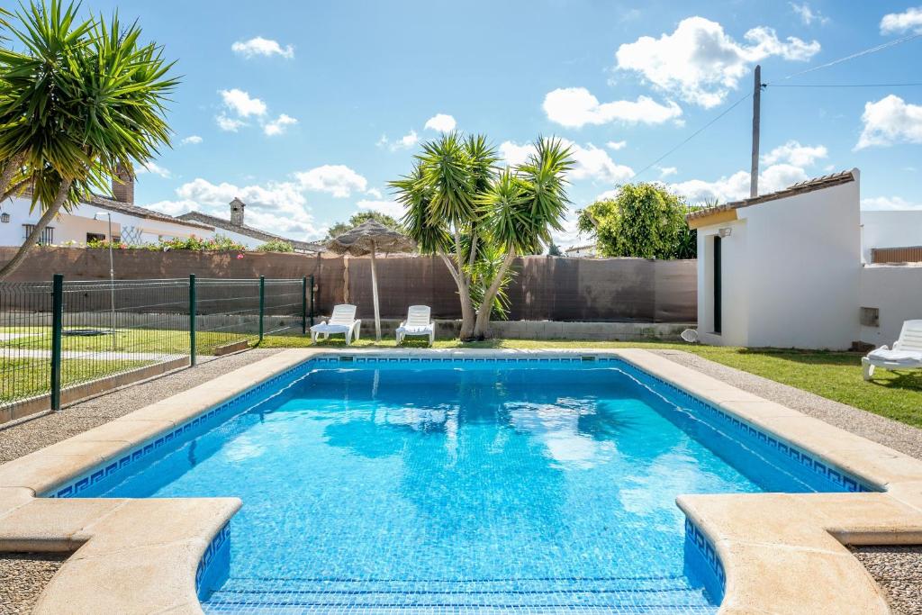 a pool with blue water in a backyard with palm trees at Casa García in Cádiz